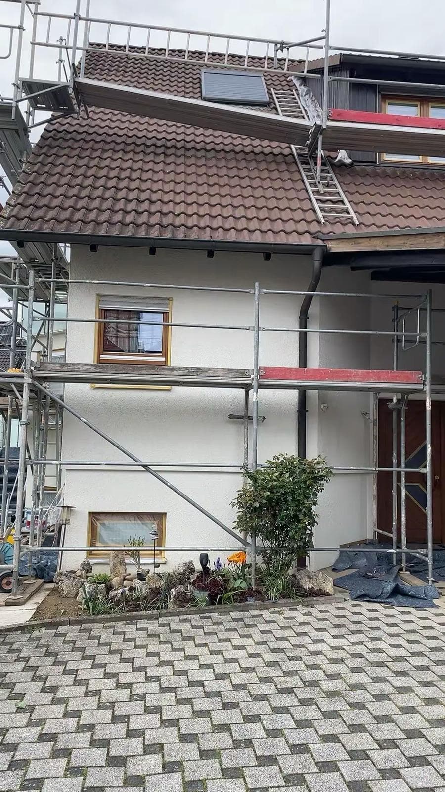 Fertiggestellte, verputzte Hausfassade mit Gerüst