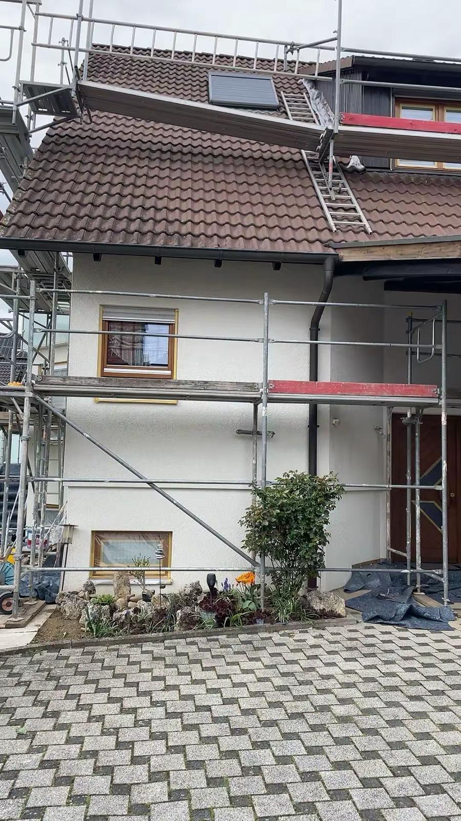 Fertiggestellte, verputzte Hausfassade mit Gerüst